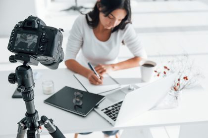 Camera recording girl. Young female freelancer working indoors in the office at daytime.